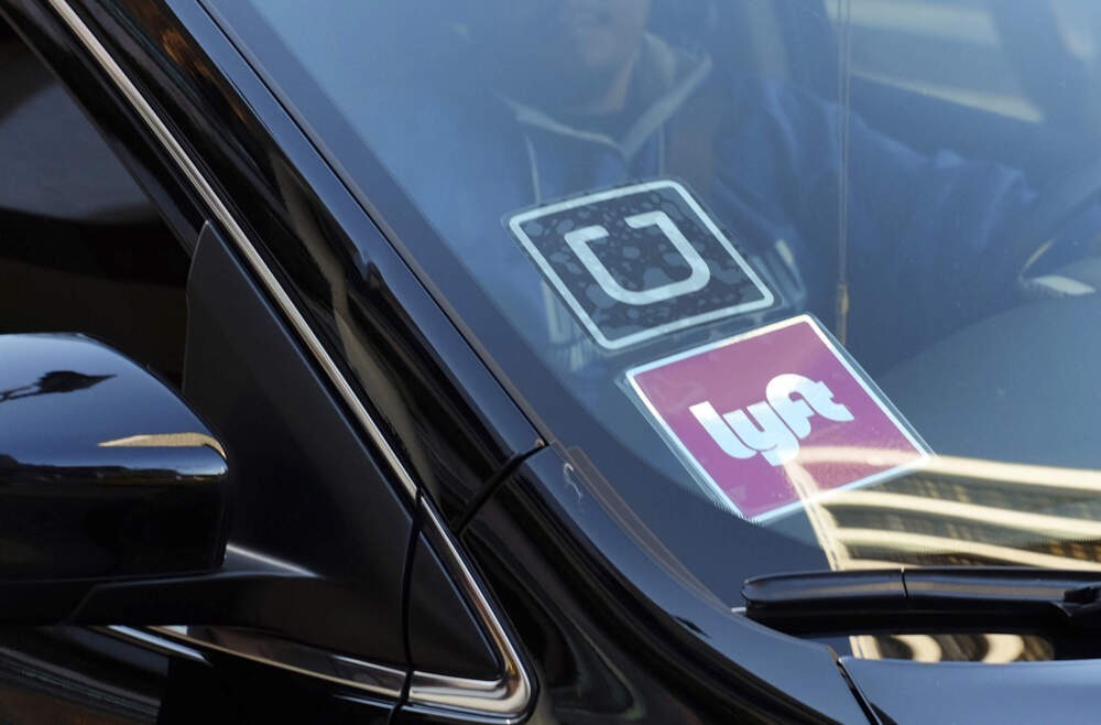 A ride share car displays Lyft and Uber stickers on its front windshield in downtown Los Angeles. (Richard Vogel/AP)